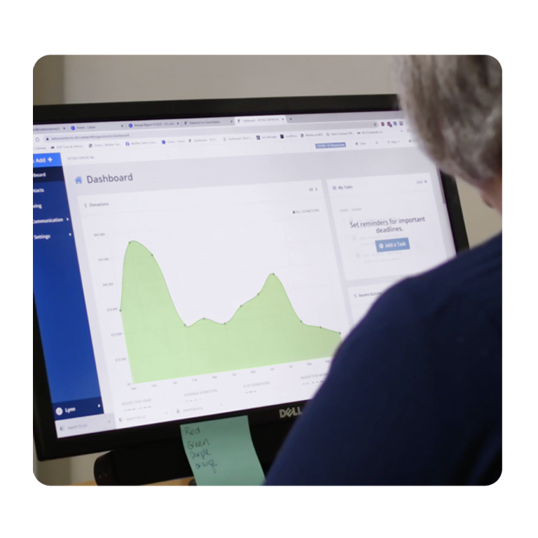 This image of a person looking at a dashboard with a graph on a computer screen represents the comprehensive reports you can gain access to through Network for Good’s fundraising software.